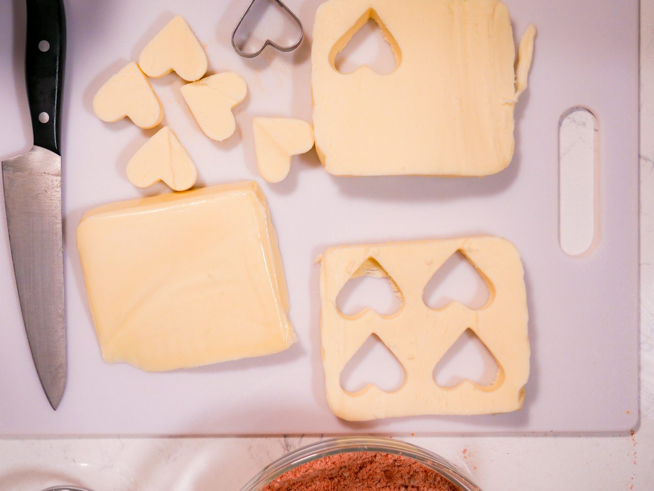 Heart-shaped mozzarella cut-out of sheets of mozzarella with heart-shaped cutter on a cutting board 