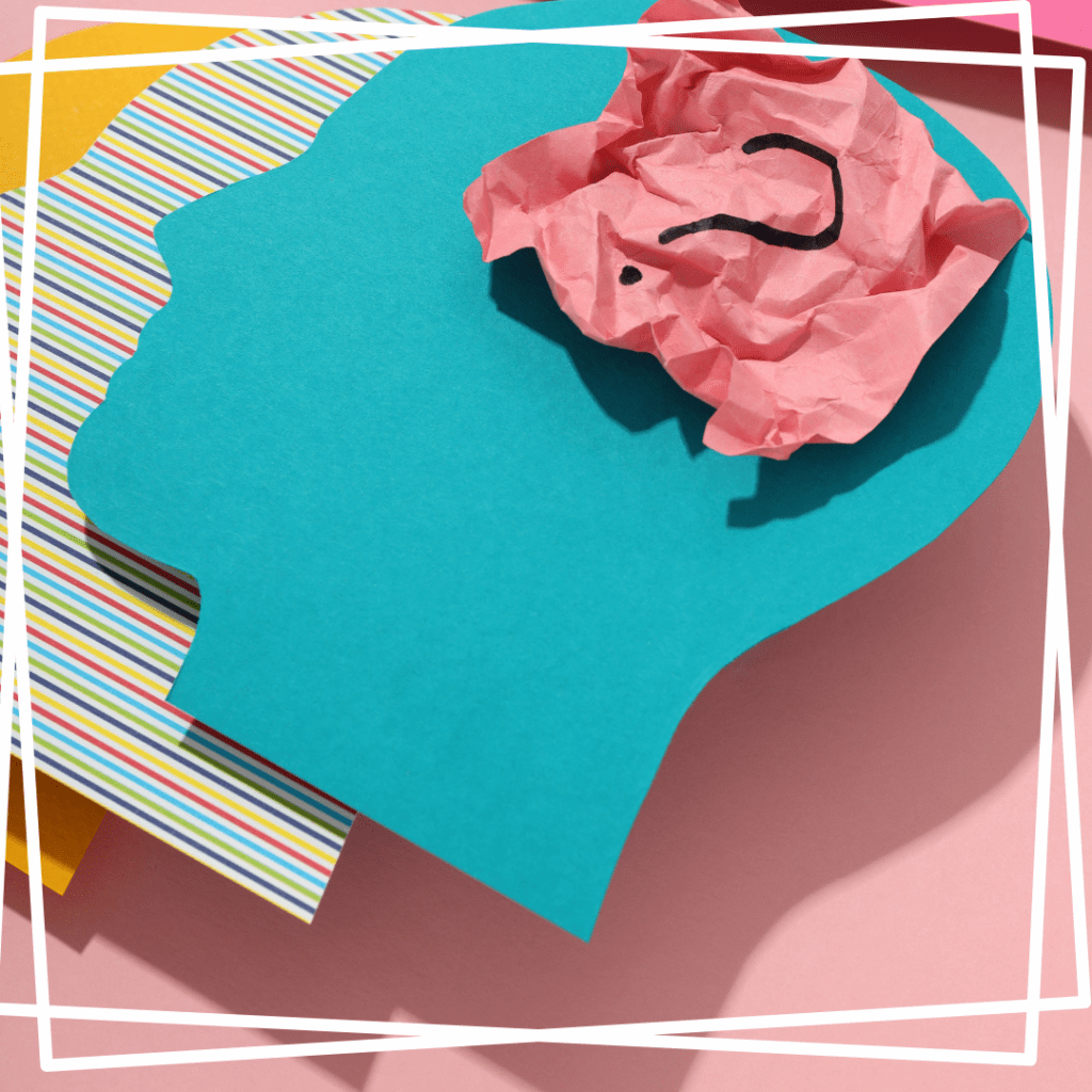 Question mark on a pink post-it note inside a teal head shaped paper cutout against a colorful paper background to represent complex ptsd and dissociation