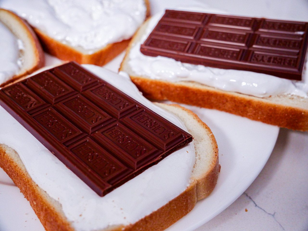 Hersheys chocolates on fluff spread on bread atop a white plate