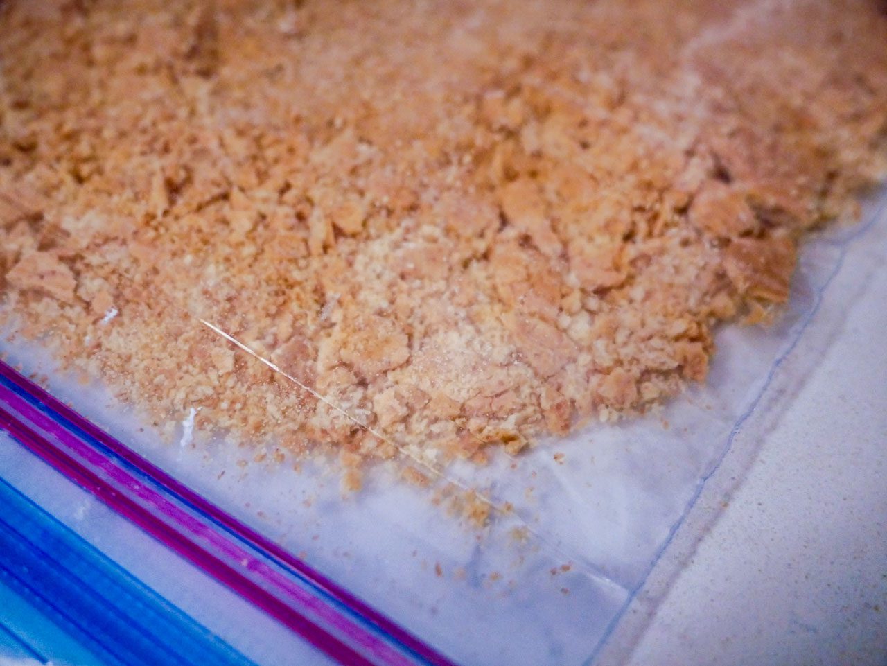 Crushed graham crackers in a ziplock bag on a white counter