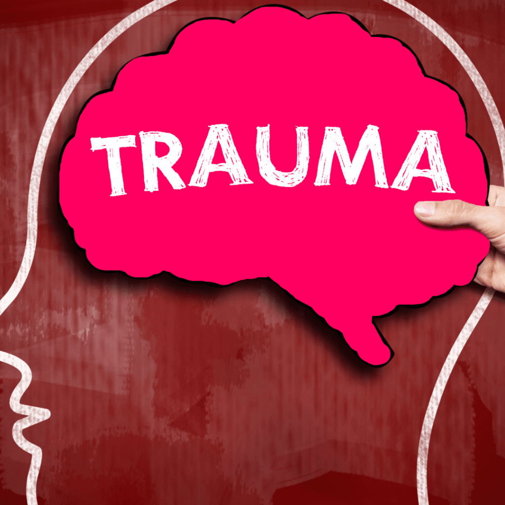 The word "trauma" in a pink thought bubble inside the silhouette of a person's head against a red chalkboard to represent complex-PTSD