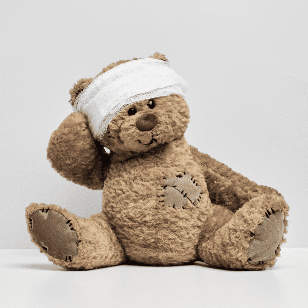 Parenting with Trauma - teddybear with arm on head. The teddybear's head is wrapped in bandages.
