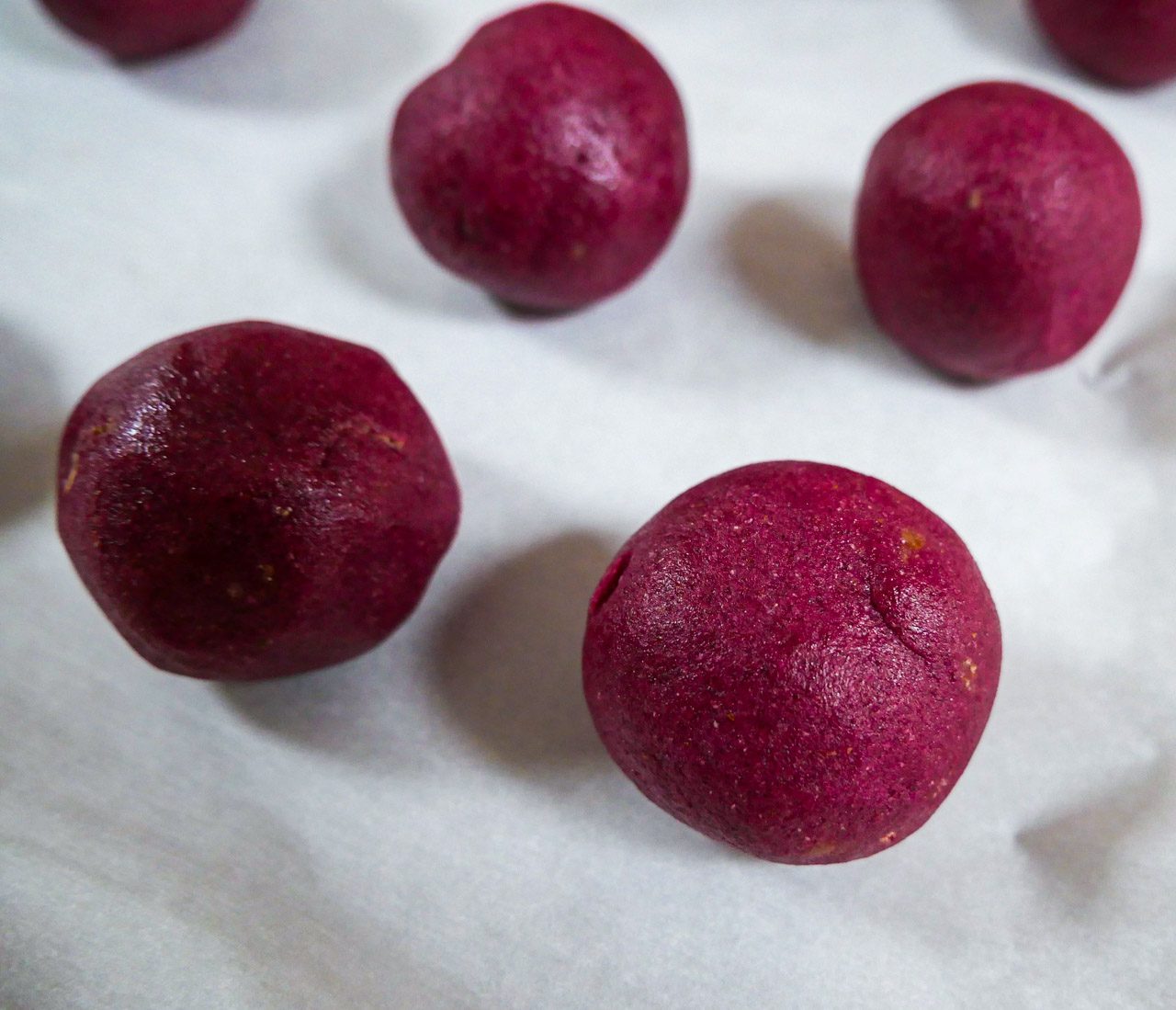 dragon fruit cookie batter rolled into balls on white parchment paper
