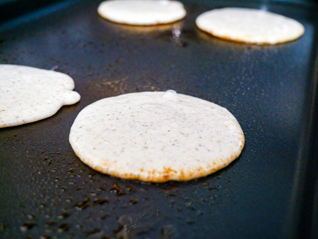 Batter on a griddle forming pancakes