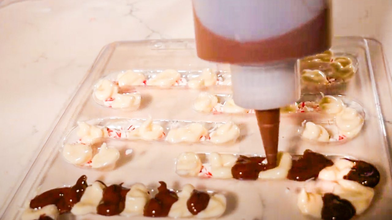 Using squeeze bottle to pipe chocolate into candy cane molds