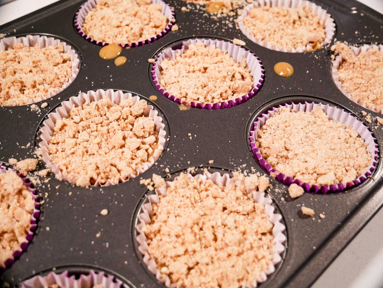 Streusel on top of plum muffin batter in cupcake pan