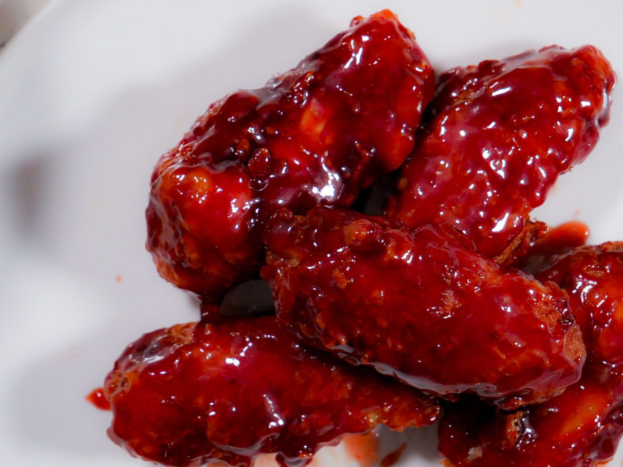 Sticky red sweet sauce on fried chicken wings on a plate