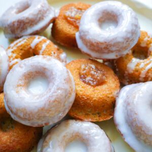 Mini donuts or mini bundts with floral glaze and apple pie filling arranged on a light yellow dish